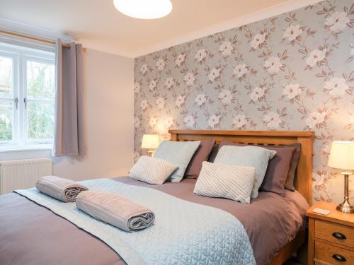 two beds in a bedroom with flowers on the wall at Poldark Cottage in Charlestown