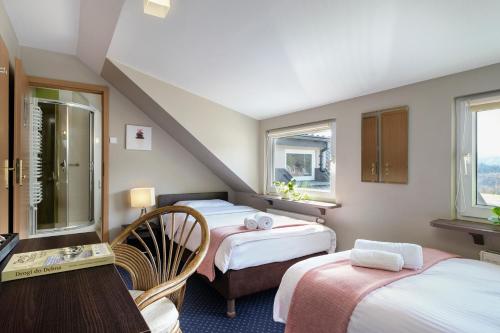 a room with three beds and a desk and windows at Pensjonat Orle in Krynica Zdrój