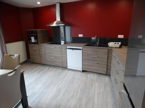 a large kitchen with red walls and a white appliance at L'estaou in Lavoûte-Chilhac