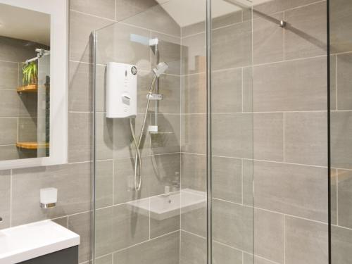 a bathroom with a shower with a glass door at Bumble Cottage in Cockermouth