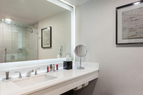 Marriott Tampa Westshore في تامبا: حمام أبيض مع حوض ومرآة