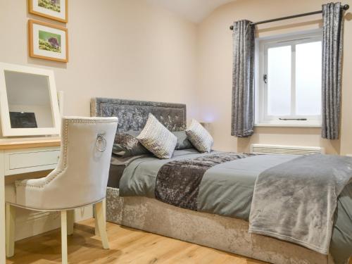 a bedroom with a bed and a desk and a chair at Bumble Cottage in Cockermouth