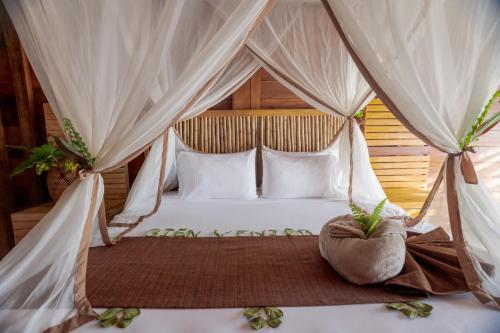 1 dormitorio con cama con dosel y almohadas blancas en Biohotel Arara River en Leticia