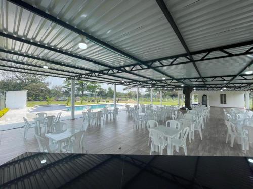 un patio con mesas y sillas blancas y una piscina en QUINTA SONAMA, en Guamal