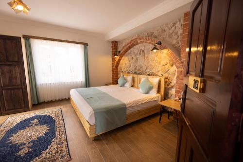 a bedroom with a bed and a brick wall at Soleado Cappadocia Hotel in Uchisar