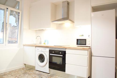 uma cozinha branca com uma máquina de lavar roupa e um micro-ondas em Apartamento FERROL VELLO II em Ferrol