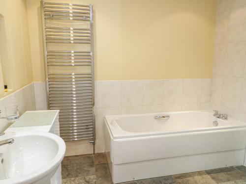 a white bathroom with a tub and a sink at No 3 The Dairy in Llangefni