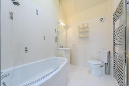 a white bathroom with a tub and a toilet at Coursehill Barn in Witney