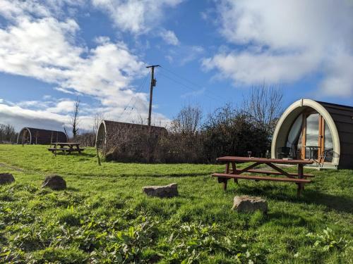 a park with two picnic tables in a field at Glamping Pod Thady Killynick County Fermanagh in Enniskillen