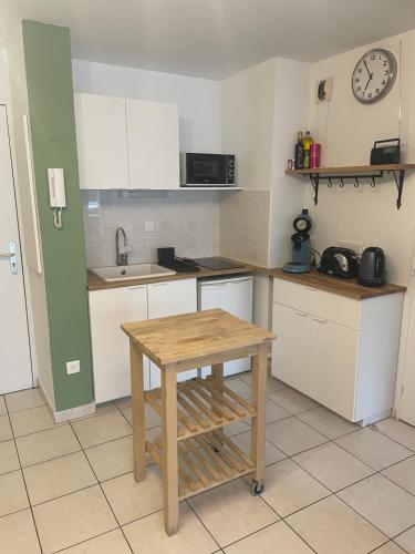 une cuisine avec une table en bois et une horloge au mur dans l'établissement Charmant Appartement Cosy sur Sète proche de toutes commodités, Parking Privé, à Sète