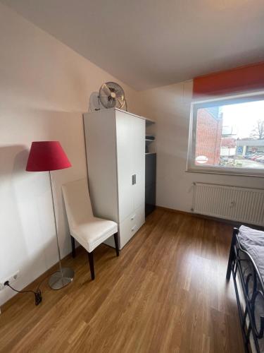 a bedroom with a white cabinet and a chair and a window at Schönes Appartement in Rheine Zentrumsnah in Rheine