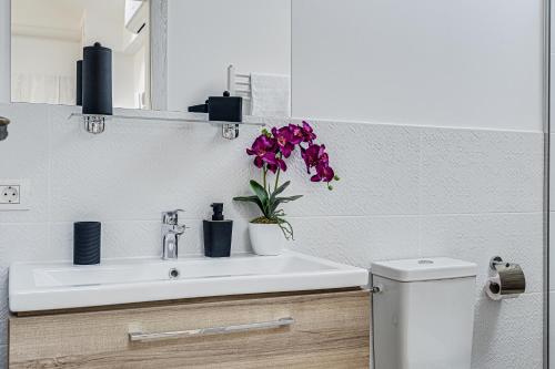 a bathroom with a sink and a toilet with purple flowers at ARI Central Skyview Apartment in Arad