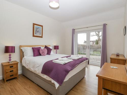 a bedroom with a large bed with purple pillows at Rectory Farm Lodge in Queen Camel