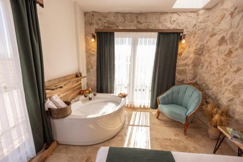 a bathroom with a tub and a chair in a room at Soleado Cappadocia Hotel in Uchisar