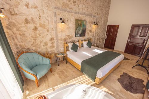 a bedroom with a bed and a chair and a tub at Soleado Cappadocia Hotel in Uchisar