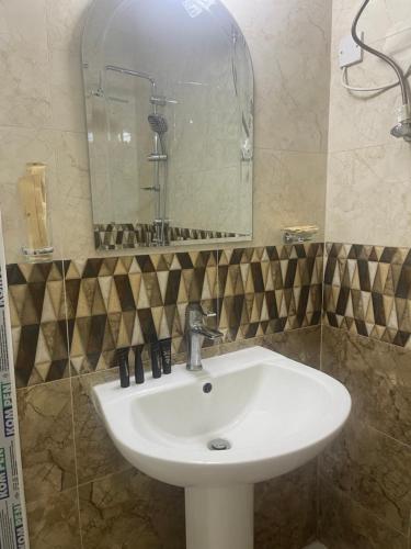 lavabo blanco en el baño con espejo en معيذر للشقق المفروشه والفندقية, en Doha