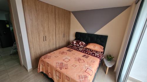 a bedroom with a bed with a comforter on it at Hermoso Apartamento Entero - Parqueadero - Pino in Ibagué