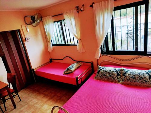 2 camas en una habitación con sábanas rosas y ventanas en Descanso en casa de familia en Salta
