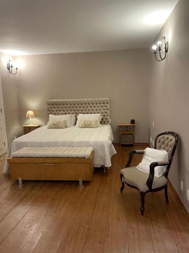 een slaapkamer met een groot bed en een stoel bij Pousada Pedra Pimenta in Tiradentes