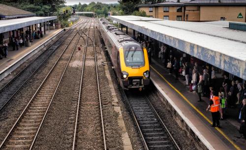 Um comboio amarelo está a chegar a uma estação de comboios. em The Botley Road House em Oxford