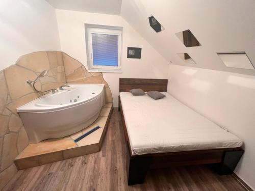 a bathroom with a tub and a bed in it at Magika in Uherský Brod
