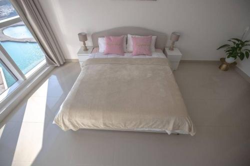 a bedroom with a bed with pink pillows and a window at We love having you here in Abu Dhabi
