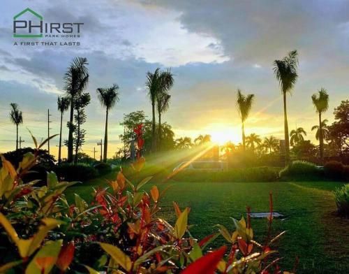 un coucher de soleil dans un parc planté de palmiers et d'herbes dans l'établissement Muji-Inspired, Studio-Type Home at Phirst Park Homes Tanza, à Tanza