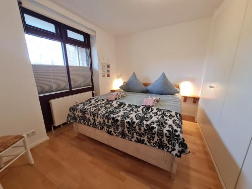 - une chambre avec un lit doté d'oreillers bleus et d'une fenêtre dans l'établissement Bi de Wyk, Whg C1, à Wyk auf Föhr