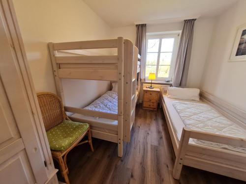 a bedroom with two bunk beds and a chair at Ferienhaus Ellen, EG Whg in Utersum
