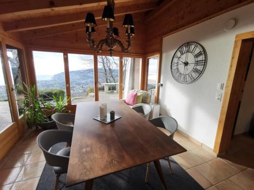 une salle à manger avec une table, des chaises et une horloge dans l'établissement Elvira House Montreux, un lieu magique !, à Montreux