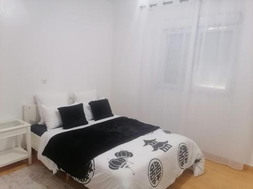 a white bedroom with a bed with black and white sheets at Huge Cozy Apartment in Larache