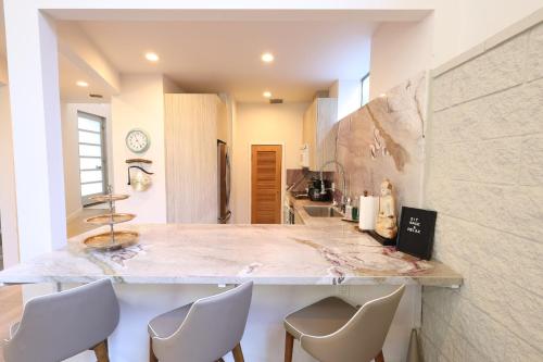 cocina con encimera de mármol y sillas blancas en The Butterfly House en Malibu