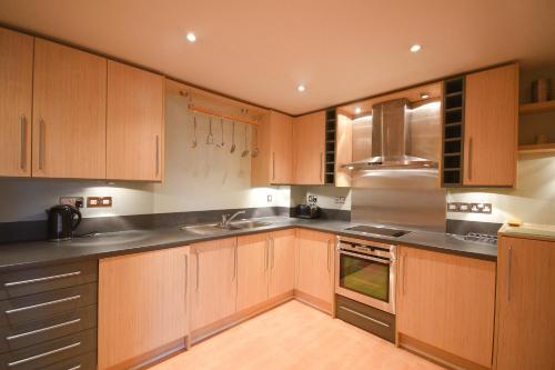 a kitchen with wooden cabinets and stainless steel appliances at Town or Country - The Greenwich in Southampton