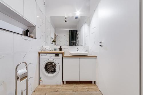 a white bathroom with a washing machine and a sink at ARI Cinema Apartament in Arad