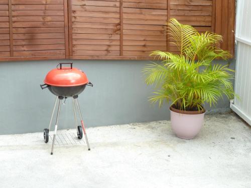 a bbq grill on a stool next to a plant at Duplex Rose Porcelaine - Vue Mer- Malendure in Bouillante