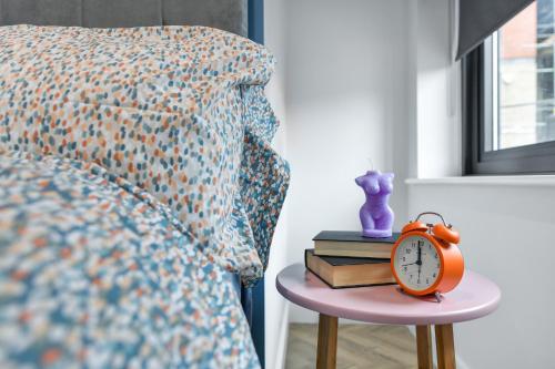 an orange clock on a table next to a bed at The Varsity Studios in Nottingham