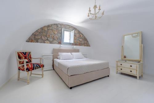 una camera da letto con un letto, una sedia e uno specchio di Red Cliff Santorini Villa - Volcano View & Jacuzzi ad Akrotírion