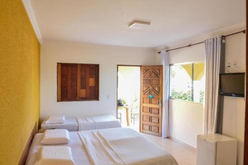 a bedroom with two beds and a door to a balcony at Praia dos Corais in Paripueira
