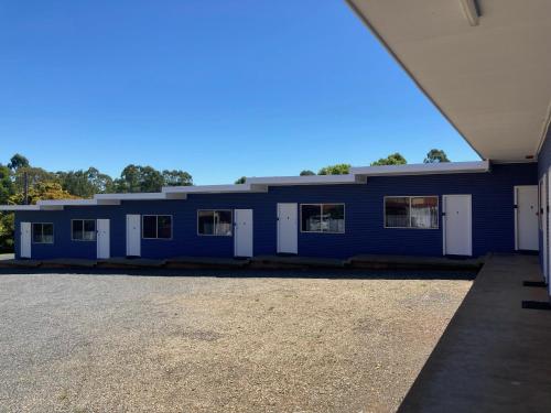 un edificio azul con puertas blancas y aparcamiento en The Frontier Motel, en Dorrigo