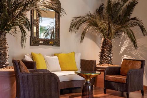 a living room with a couch and two palm trees at Best Western Premier Montfleuri in Sainte-Maxime