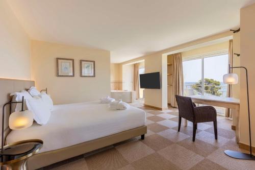 een hotelkamer met een bed, een bureau en een televisie bij Best Western Premier Montfleuri in Sainte-Maxime