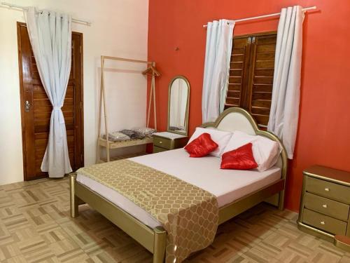 sypialnia z łóżkiem z czerwonymi poduszkami i lustrem w obiekcie Happy Hostel e Pousada Paracuru w mieście Paracuru