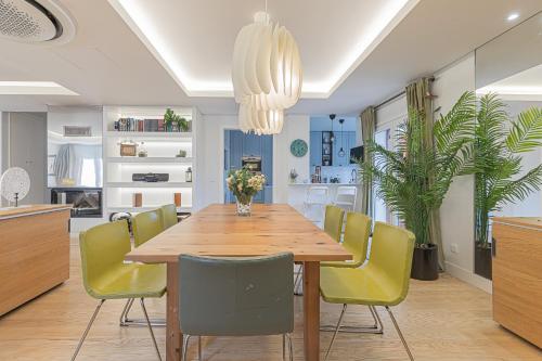 a dining room with a wooden table and yellow chairs at Villa Whiteloft Pool Spa Lounge in Corroios