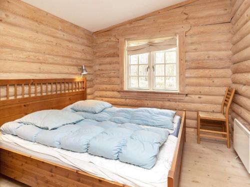 NordostにあるHoliday Home Kulmulevejの木製の壁のベッドルーム1室、青い枕付きのベッド1台が備わります。