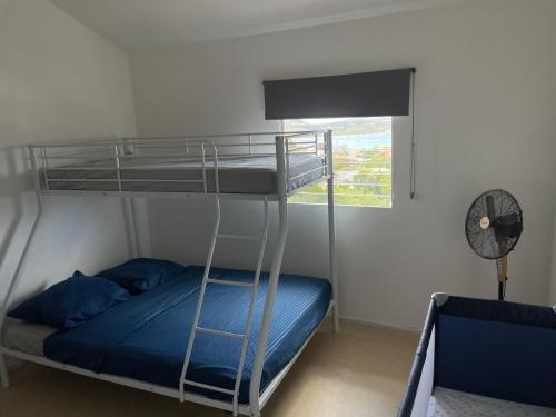 - une chambre avec un lit superposé doté d'oreillers bleus et d'une fenêtre dans l'établissement Maison Bel bonjou, au Marin