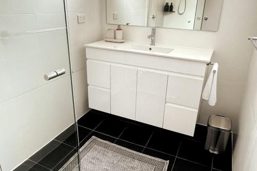 a white bathroom with a sink and a mirror at The Retreat Terrigal 3bed 100m to beach in Terrigal