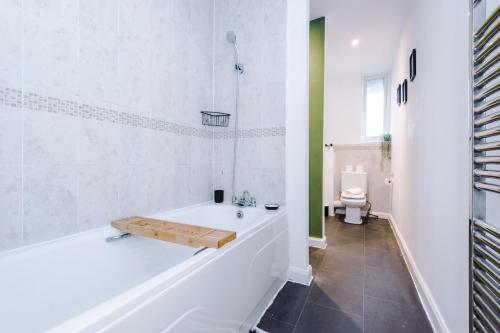 baño blanco con bañera y aseo en Rest&Recharge at a Spacious Townhouse by the Etihad (5mins to City Centre, Free Secure Parking) en Mánchester
