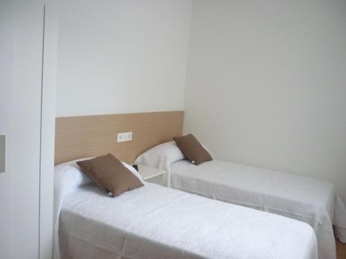 two beds in a small room with white walls at Pensión-Albergue Puente Ribeira in Sarria
