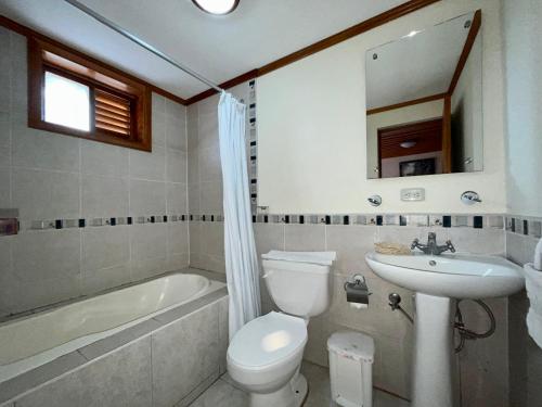 a bathroom with a toilet and a sink and a tub at Hostería La Condesa in Honorato Vásquez