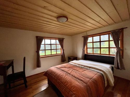 a bedroom with a bed and two windows at Hostería La Condesa in Honorato Vásquez